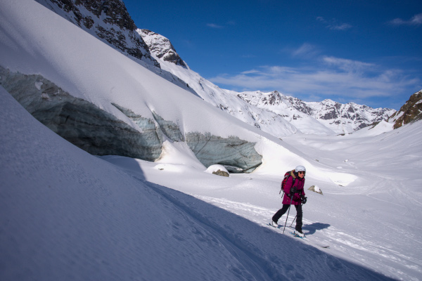 Femme qui fait du ski de randonnée à la sortie d'une grotte de glace.